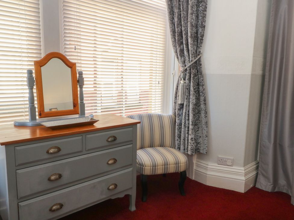 A bedroom with a dresser and striped chair at Apartment 1