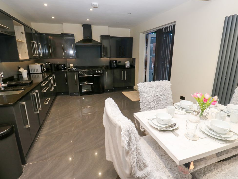 A kitchen with cabinets, appliances and a dining area at Middleton Park House in Leeds