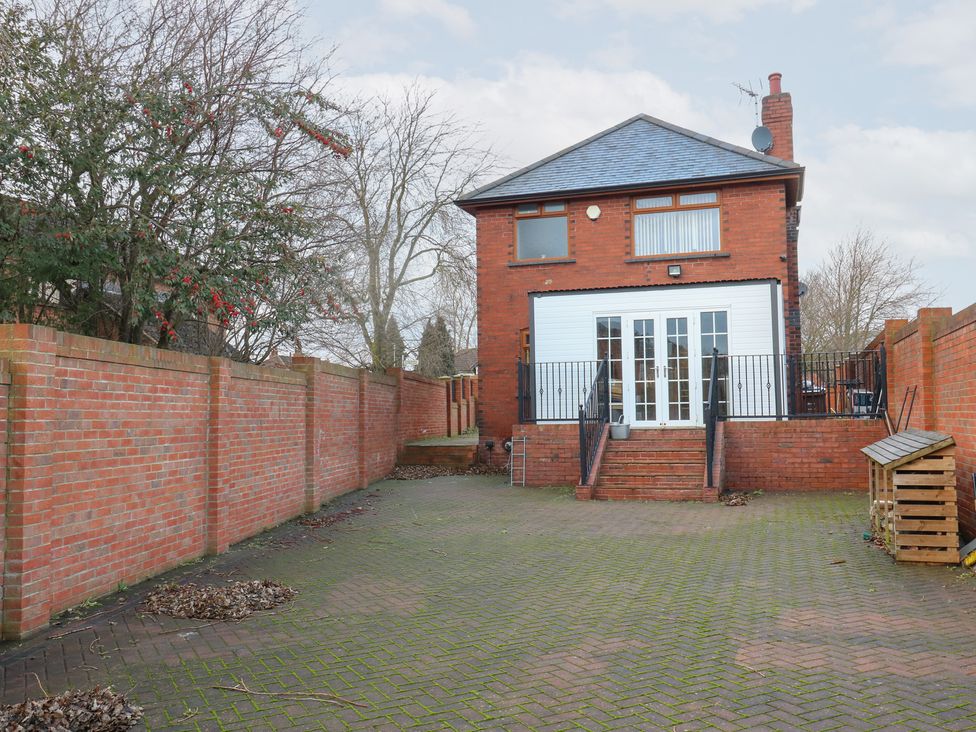 A garden with a house and patio area at Middleton Park House Leeds