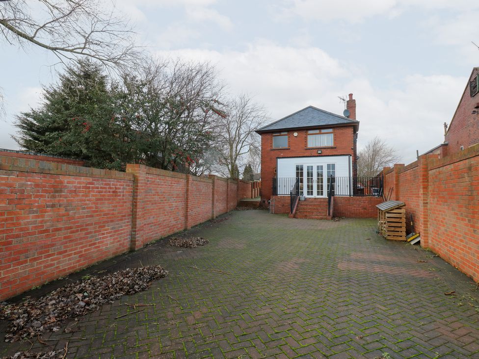 A garden with a house and brick walls at Middleton Park House Leeds