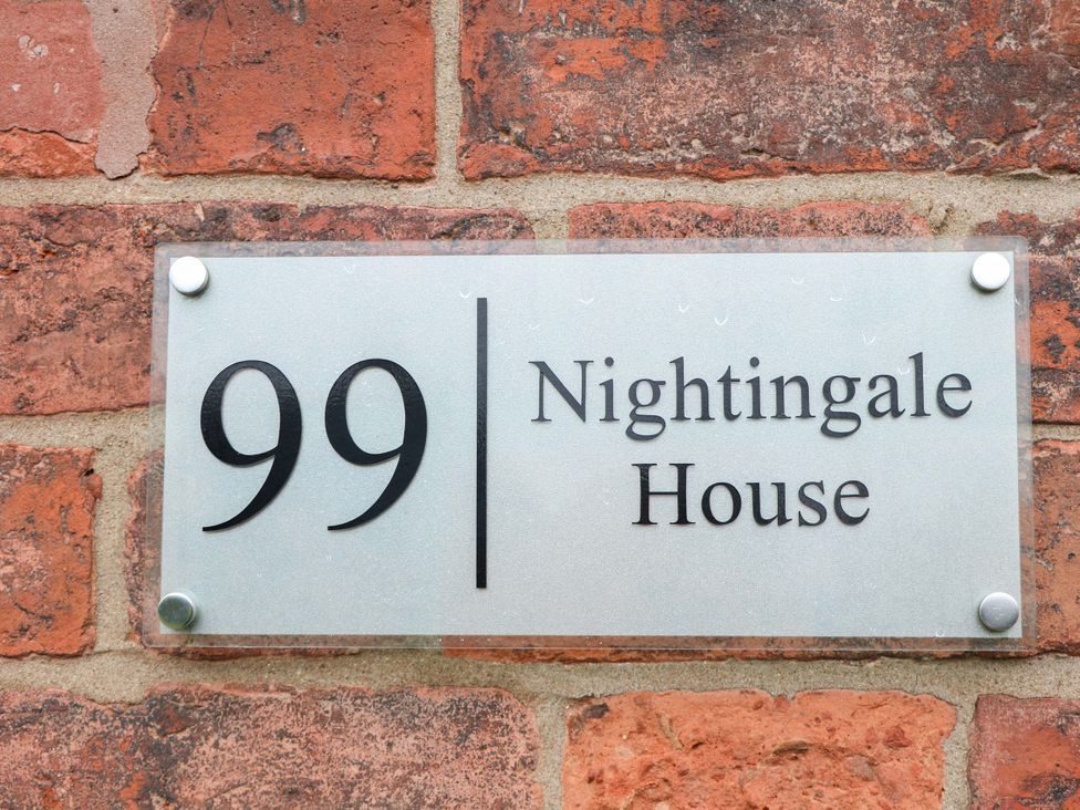 A house nameplate displaying 99 Nightingale House on a brick wall