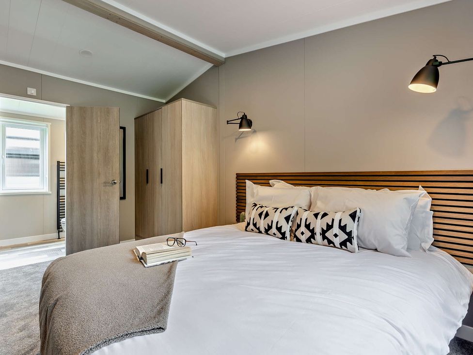 A bedroom with a bed and wardrobe at Saron 2.0 Spa Pet in Llandyrnog