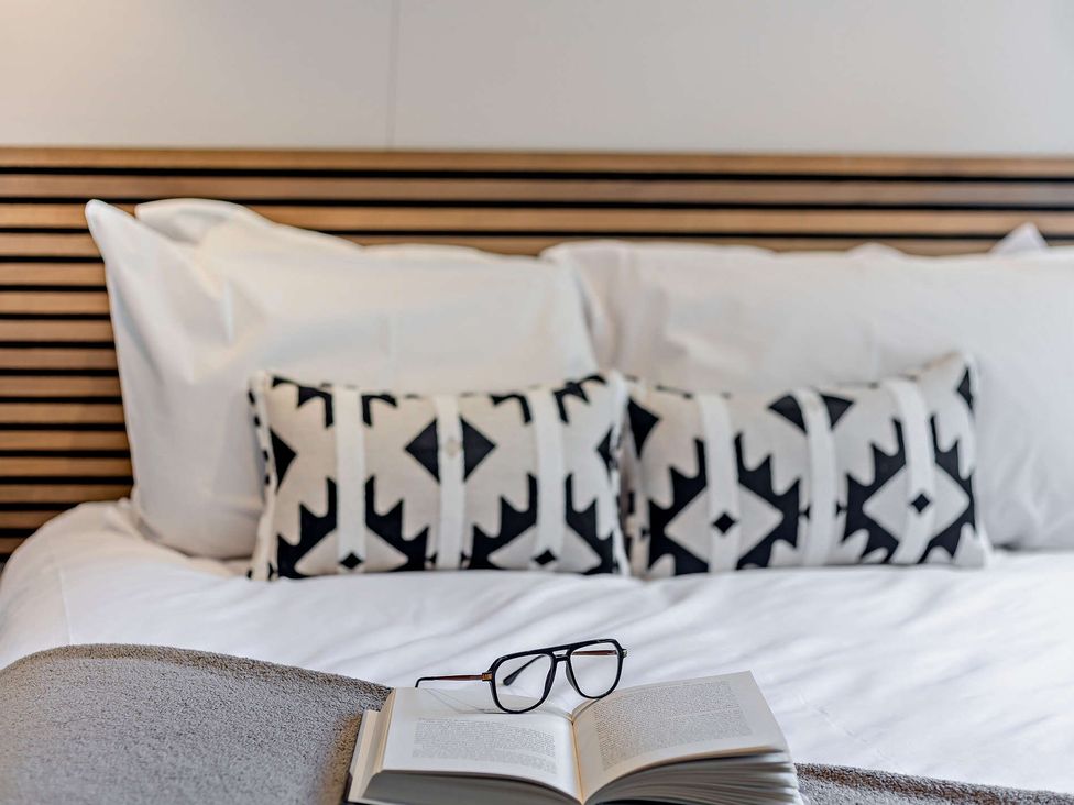 A bed with pillows and a book with glasses on top at Saron 2.0 Pet in Llandyrnog