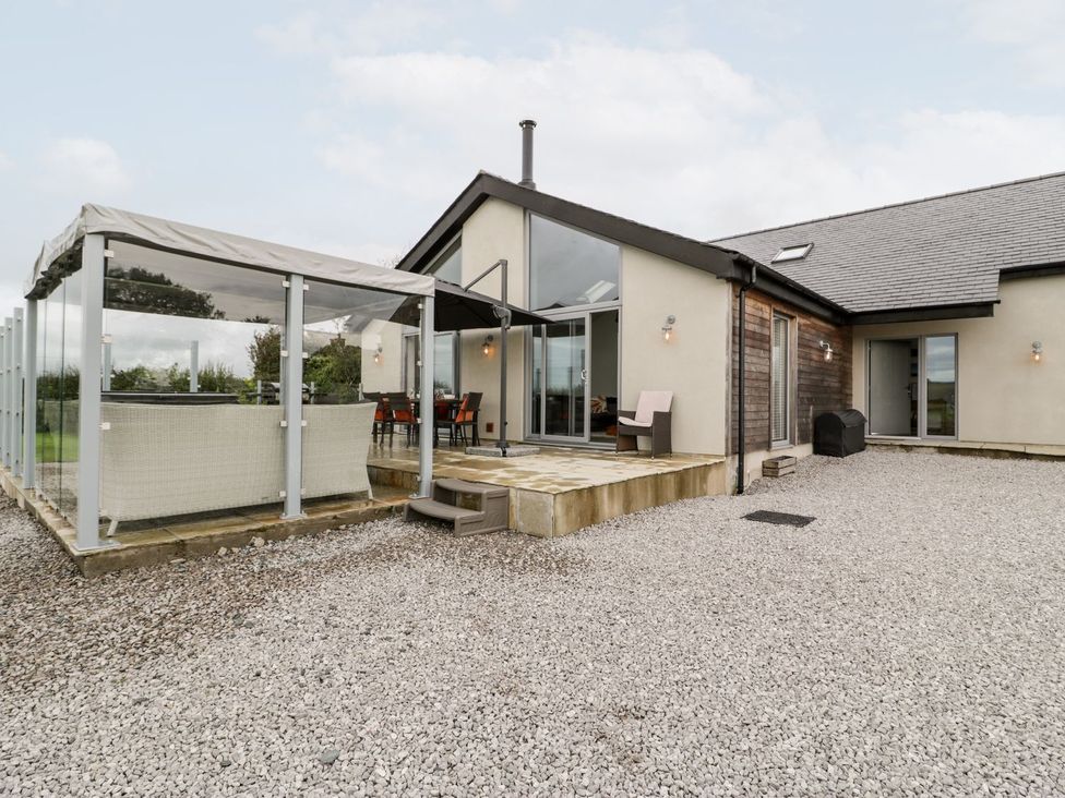 An outdoor area with seating and a glass enclosure at Cae Sam in Pentraeth