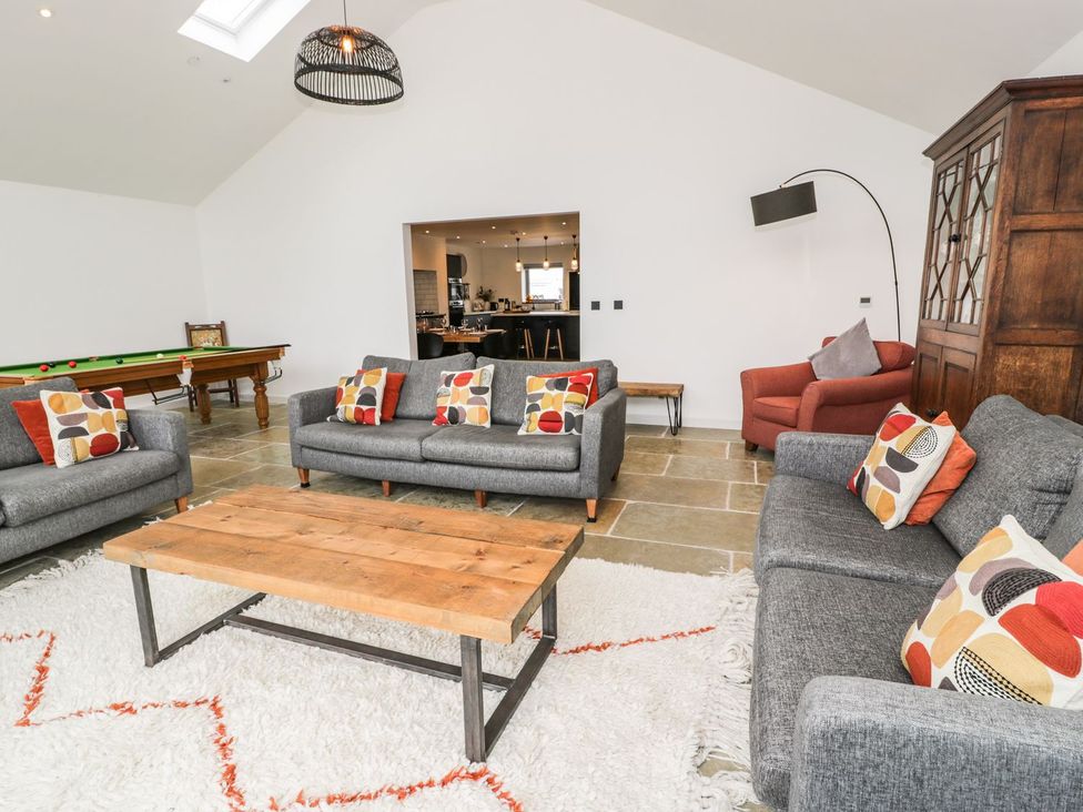 A living room with sofas, coffee table, and pool table at Cae Sam in Pentraeth