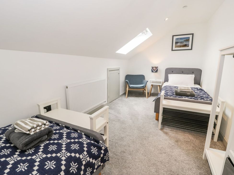 A bedroom with two beds and a chair at Cae Sam in Pentraeth