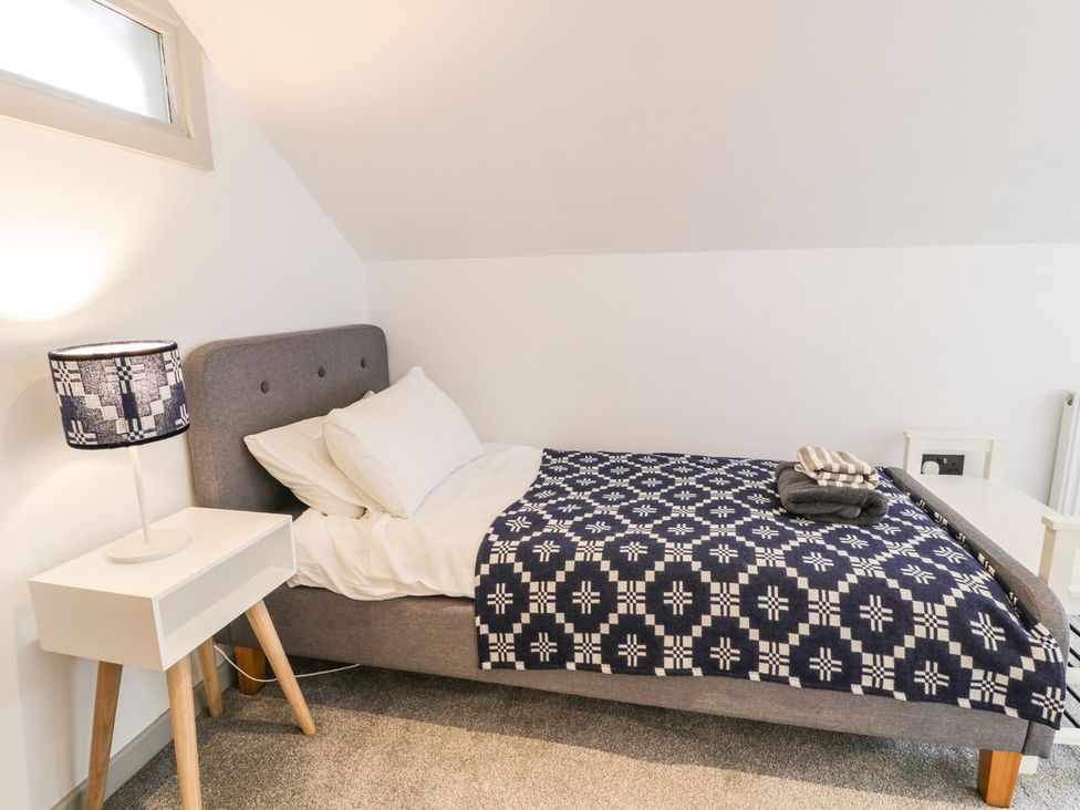 A bedroom with a bed and lamp at Cae Sam in Pentraeth