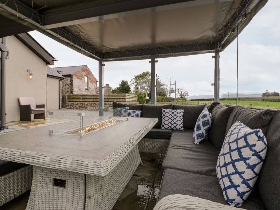 An outdoor living area with seating and a fire pit at Cae Sam in Pentraeth