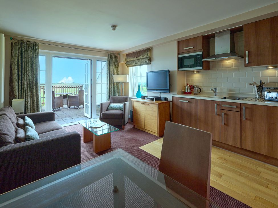 A living room with a sofa and kitchen area at Duplex Apartment Penrith