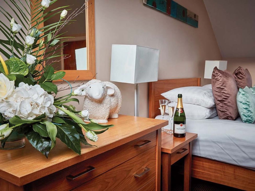 A bedside table with flowers and a champagne bottle in a bedroom at Duplex Apartment in Penrith