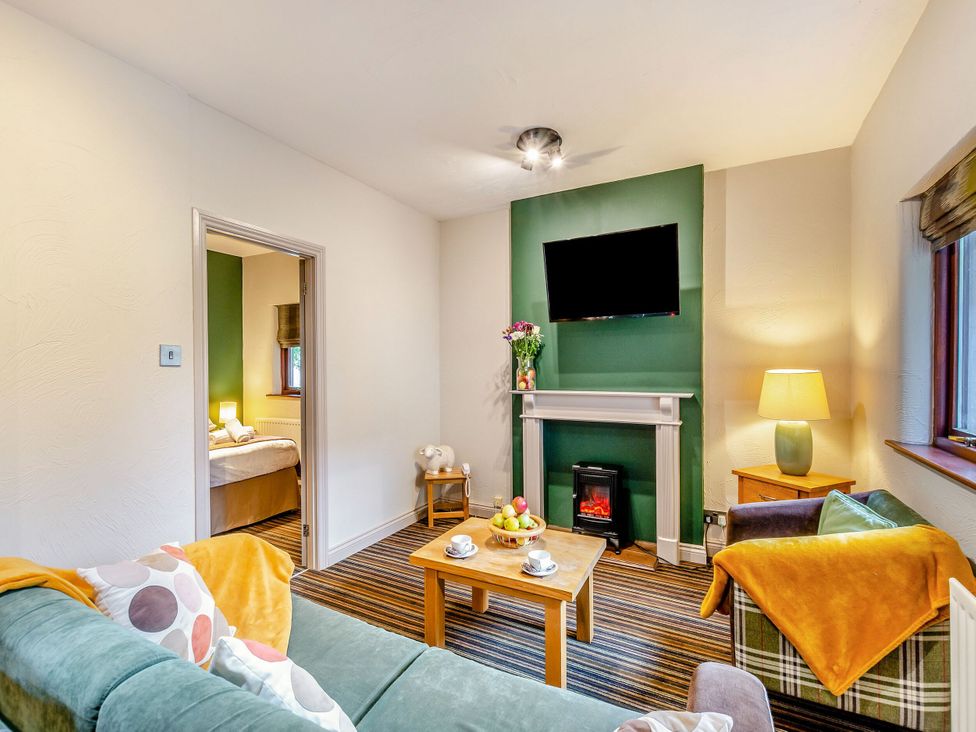A living room with a sofa, television and table at Skiddaw in Penrith