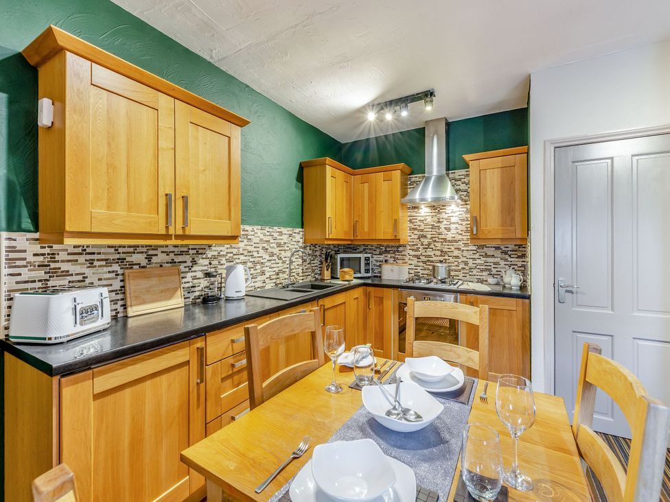 A kitchen with wooden cabinets and dining table at Skiddaw in Penrith