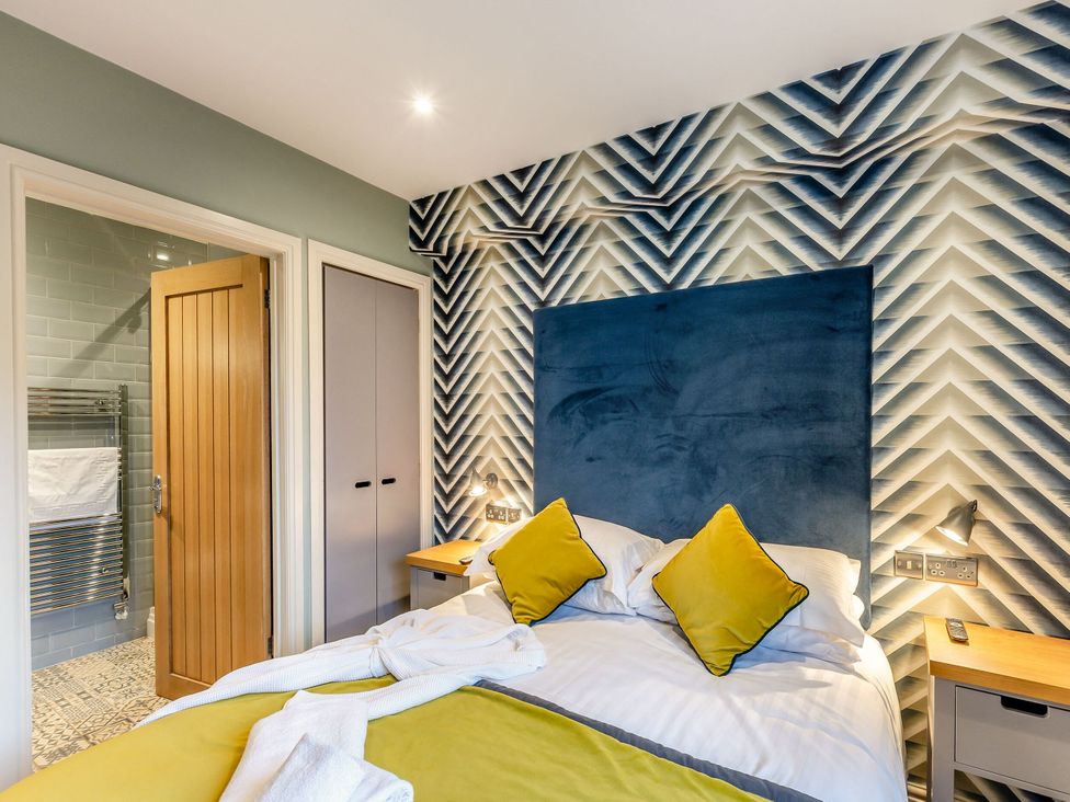 A bedroom with a bed and a wooden door at The Whitbarrow Den in Penrith