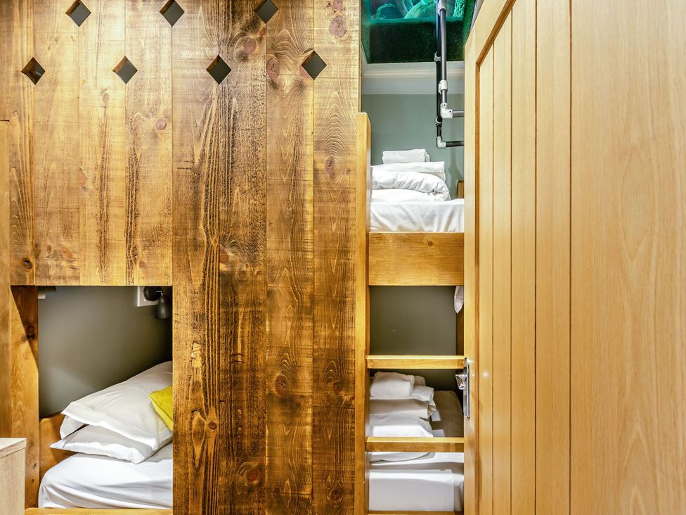 A bedroom with a wooden wall and bunk beds at The Whitbarrow Den in Penrith