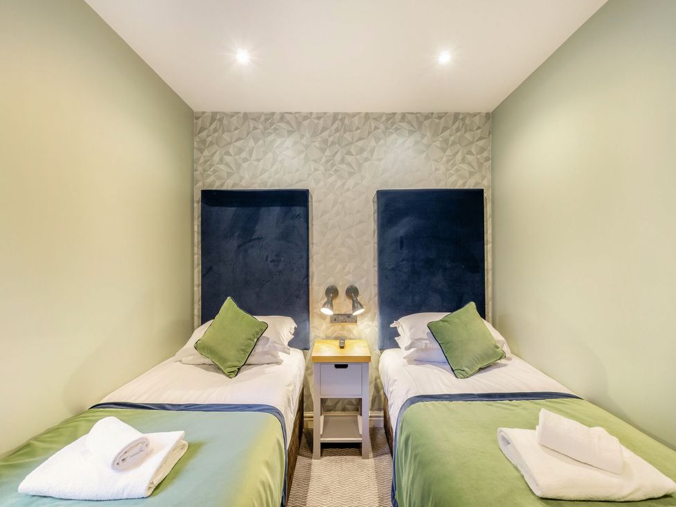 A bedroom with two beds and a nightstand at The Whitbarrow Den in Penrith