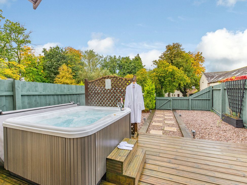 A hot tub with a robe and towel in the garden at Caldew Cottage Spa Penrith