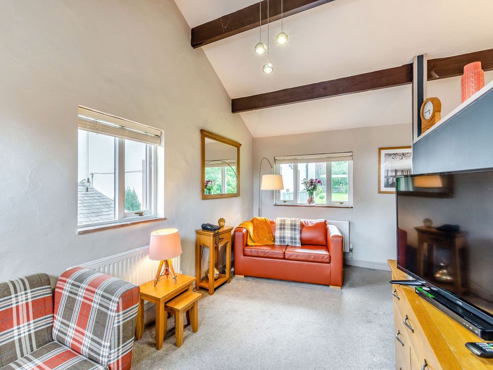 A living room with a sofa and TV at Caldew Cottage Spa in Penrith