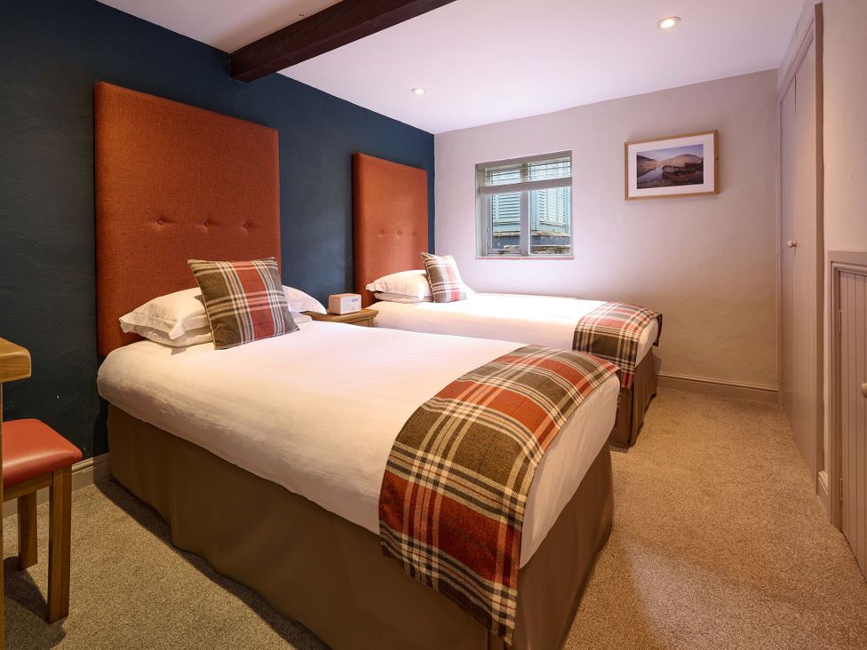 A bedroom with two beds and a window at Caldew Cottage Spa in Penrith