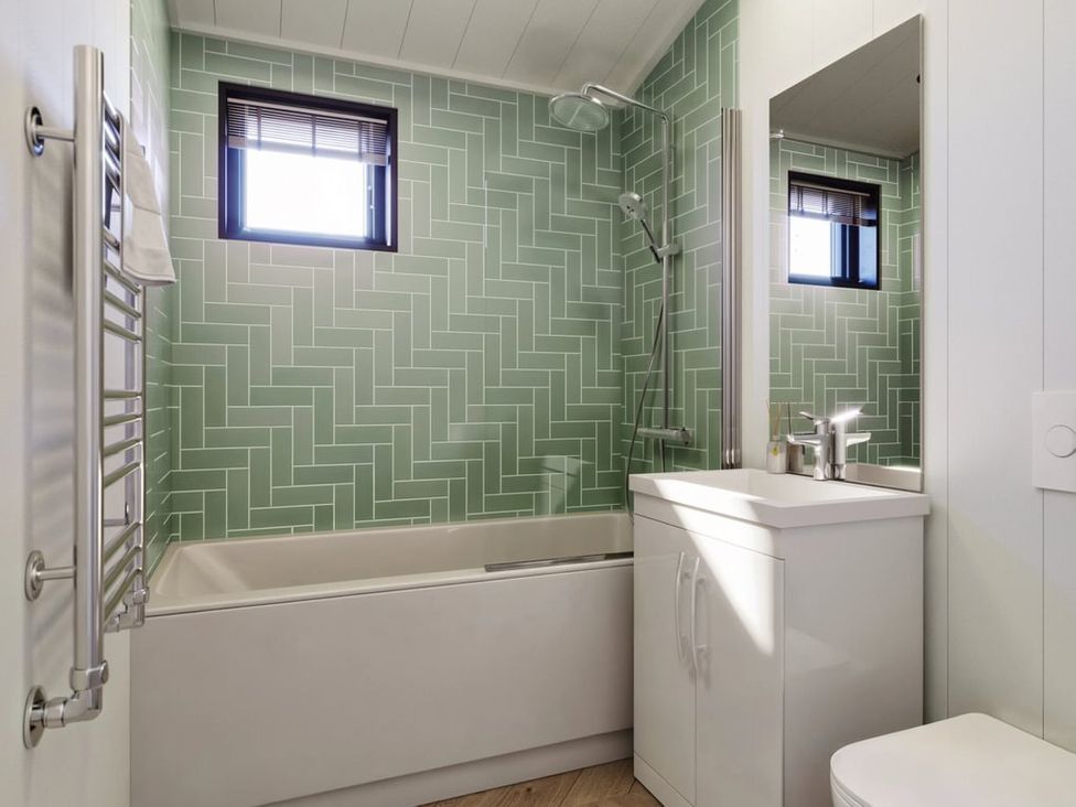 A bathroom with a bathtub, shower, sink, and towel warmer at Hesk in Penrith