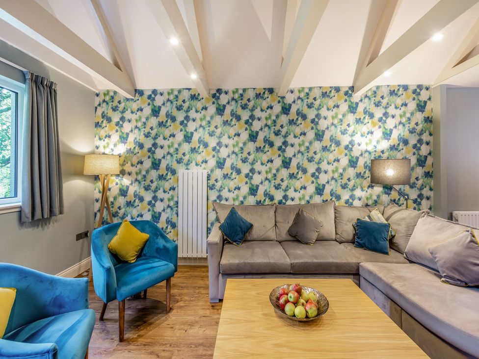 A living room with a sofa, armchairs, and a coffee table at Troutbeck Cottage Spa in Penrith