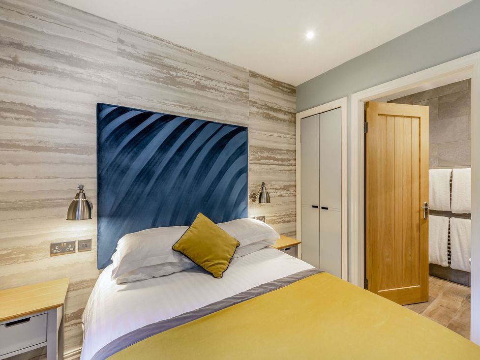 A bedroom with a bed and wardrobe at Troutbeck Cottage Spa in Penrith