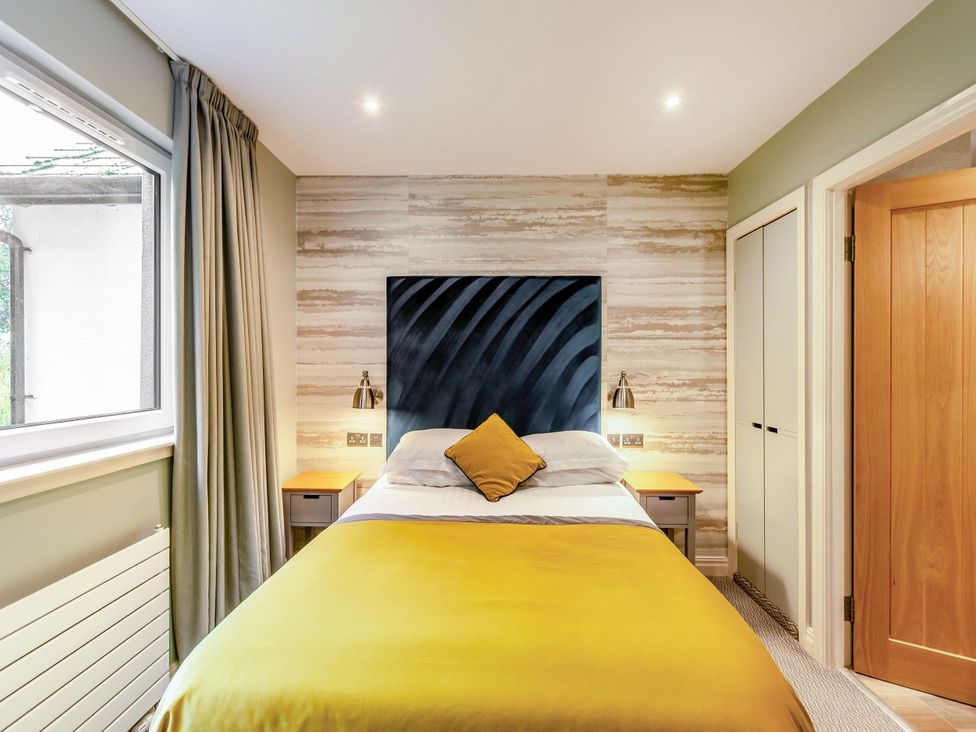 A bedroom with a bed and bedside table at The Troutbeck Den Spa Penrith