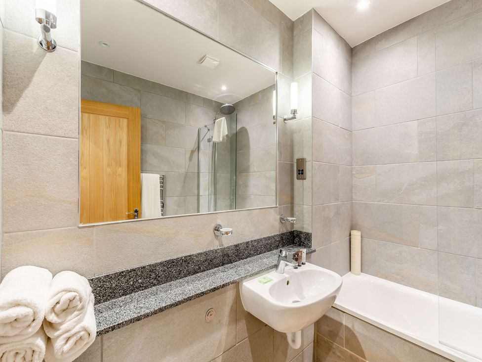 A bathroom with a bathtub and sink at The Troutbeck Den Spa in Penrith