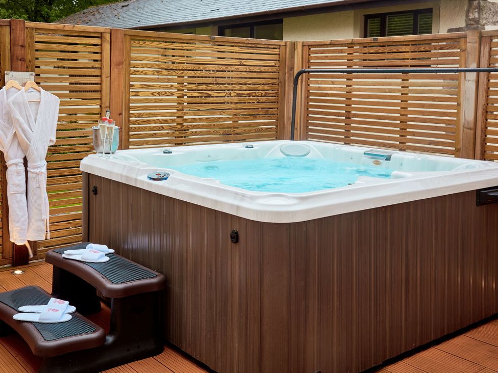 An outdoor area with a hot tub and wooden panel fence at The Farmhouse 2 Penrith