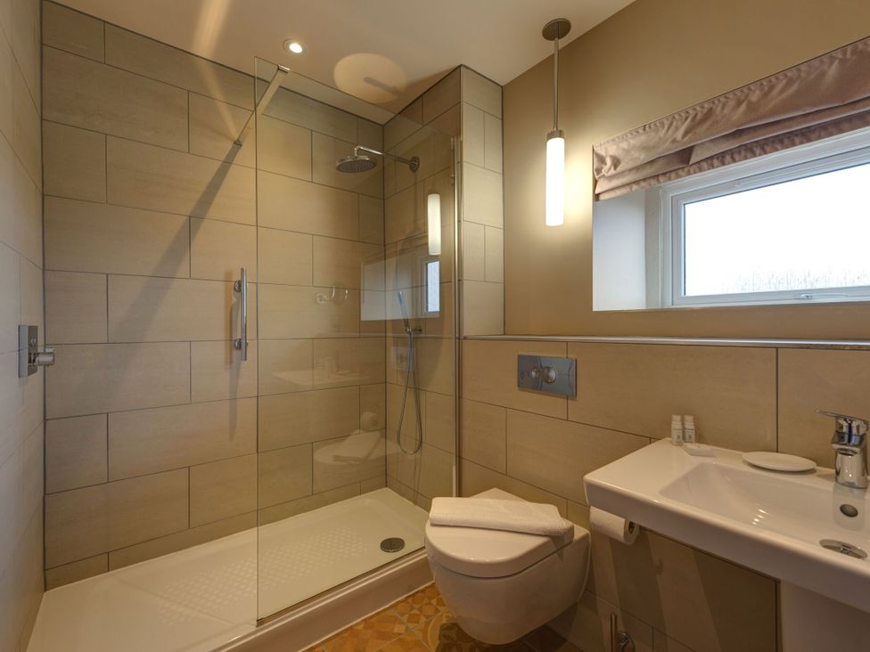 A bathroom with a shower cubicle and a sink at The Farmhouse 2 Penrith