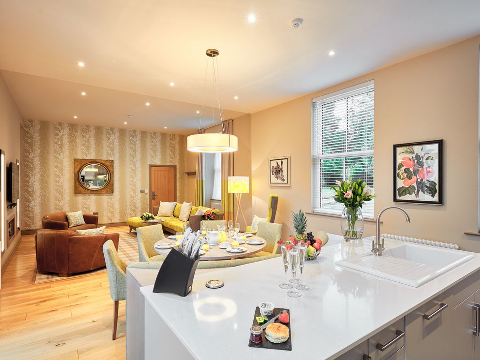 An open-plan living area with a sofa, dining table, and kitchen at The Farmhouse 1 in Penrith