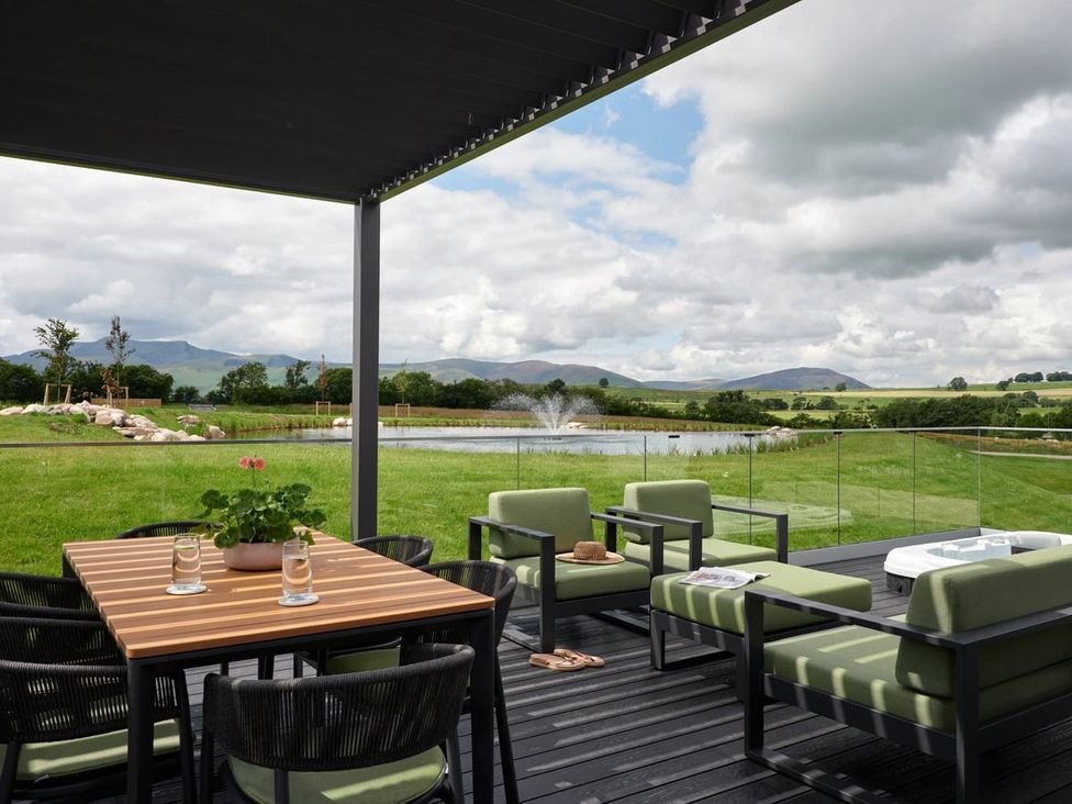 An outdoor seating area with a table and chairs overlooking a lake at Wansfell in Penrith
