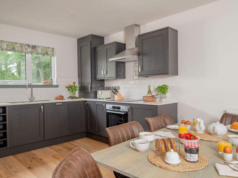 A kitchen with cabinets and dining table at Patterdale (Pet) Penrith