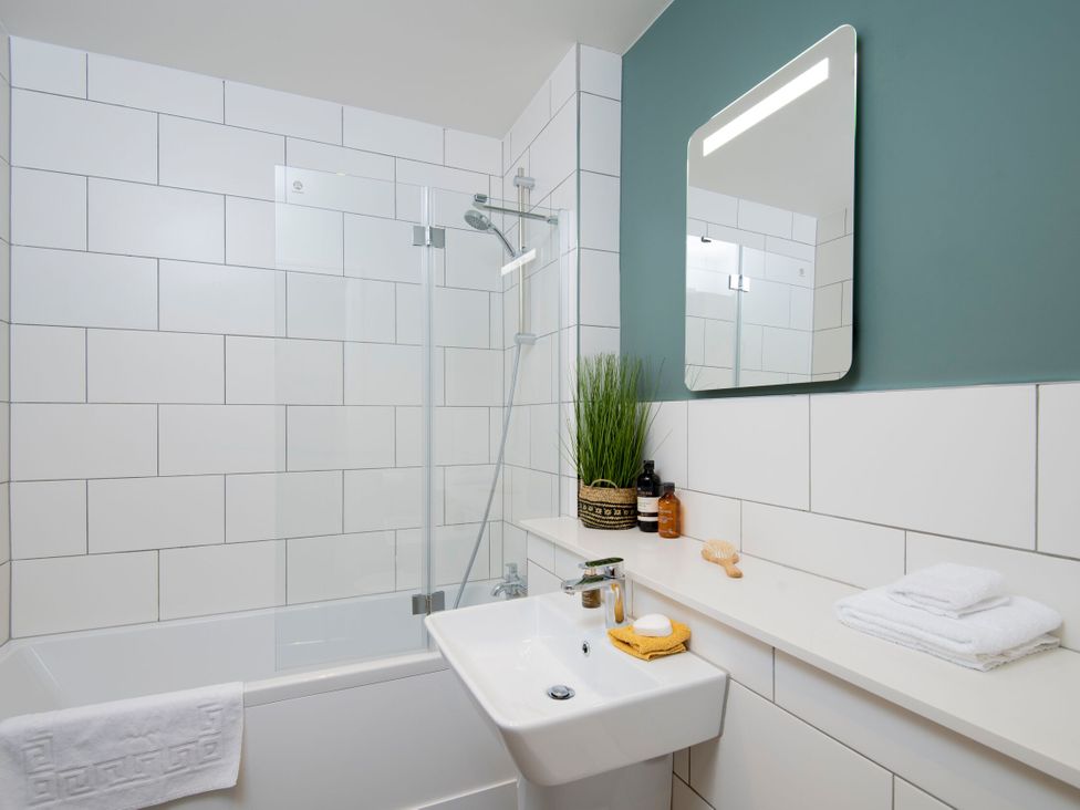 A bathroom with a bathtub, sink and mirror at Patterdale (Pet) Penrith