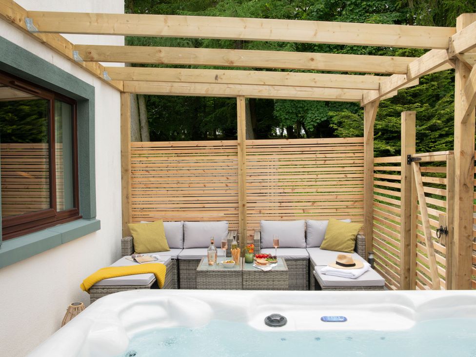 An outdoor seating area with a hot tub and a table at Patterdale (Pet) in Penrith