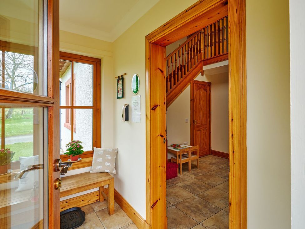 A hallway with a bench and staircase at Holly House in Blairgowrie