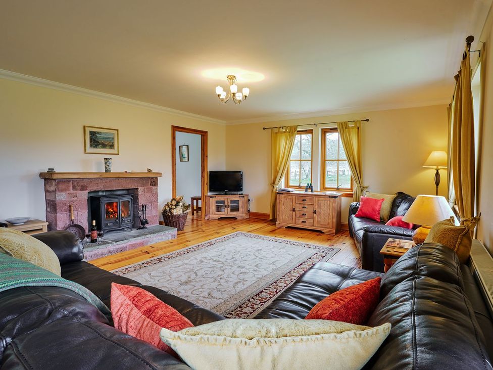 A living room with a fireplace and television at Holly House in Blairgowrie