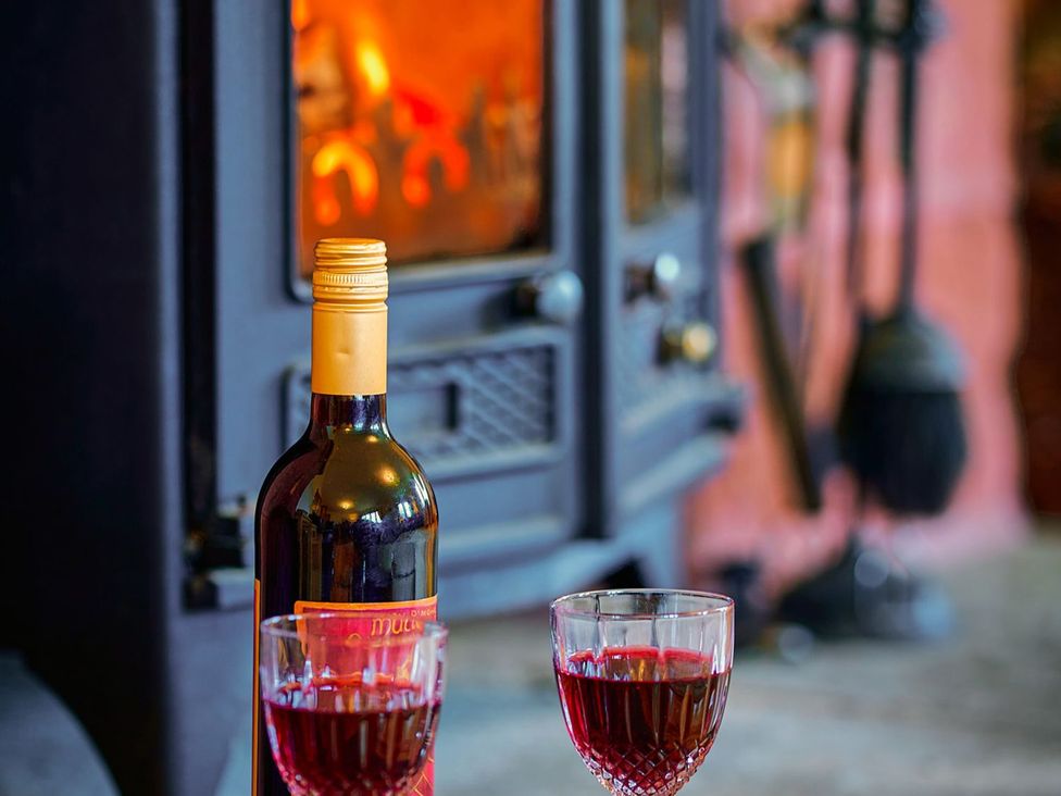A living room with wine glasses and a bottle in front of a fireplace at Holly House in Blairgowrie