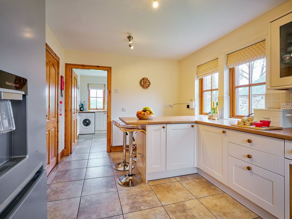 A kitchen with a counter and bar stools at Holly House in Blairgowrie