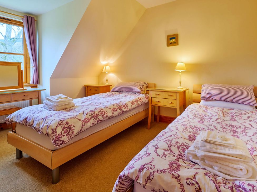 A bedroom with two beds and a nightstand at Holly House, Blairgowrie