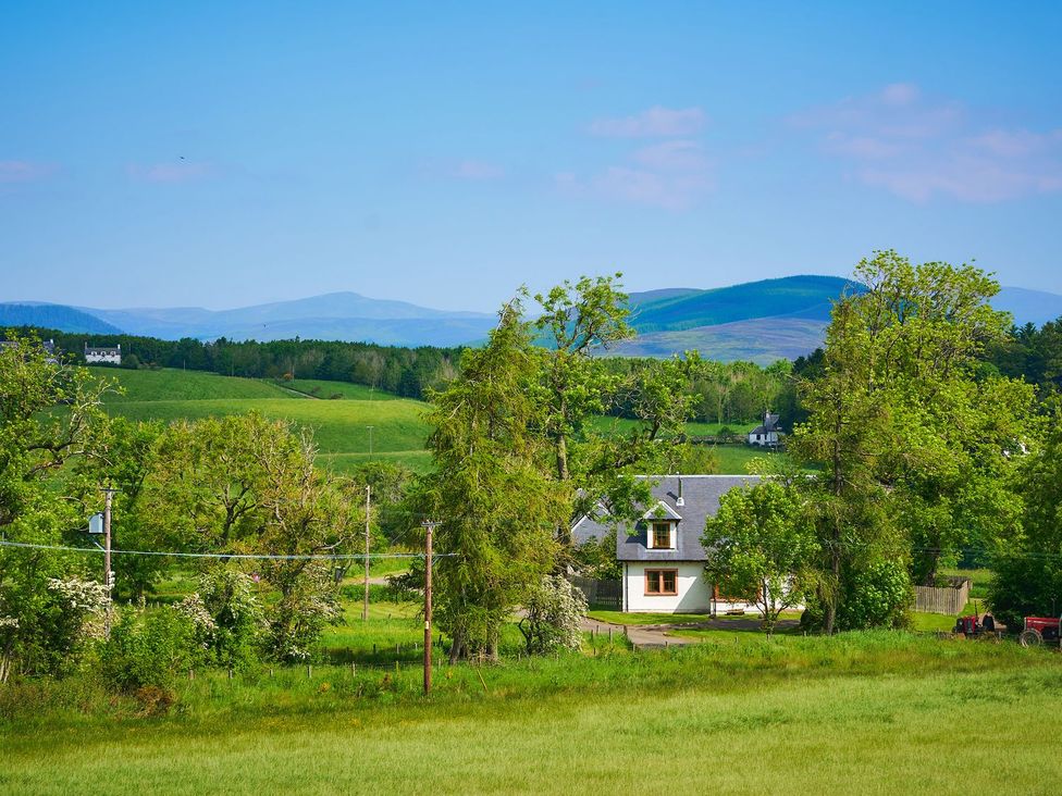 A house with trees and hills in the background at Holly House in Blairgowrie