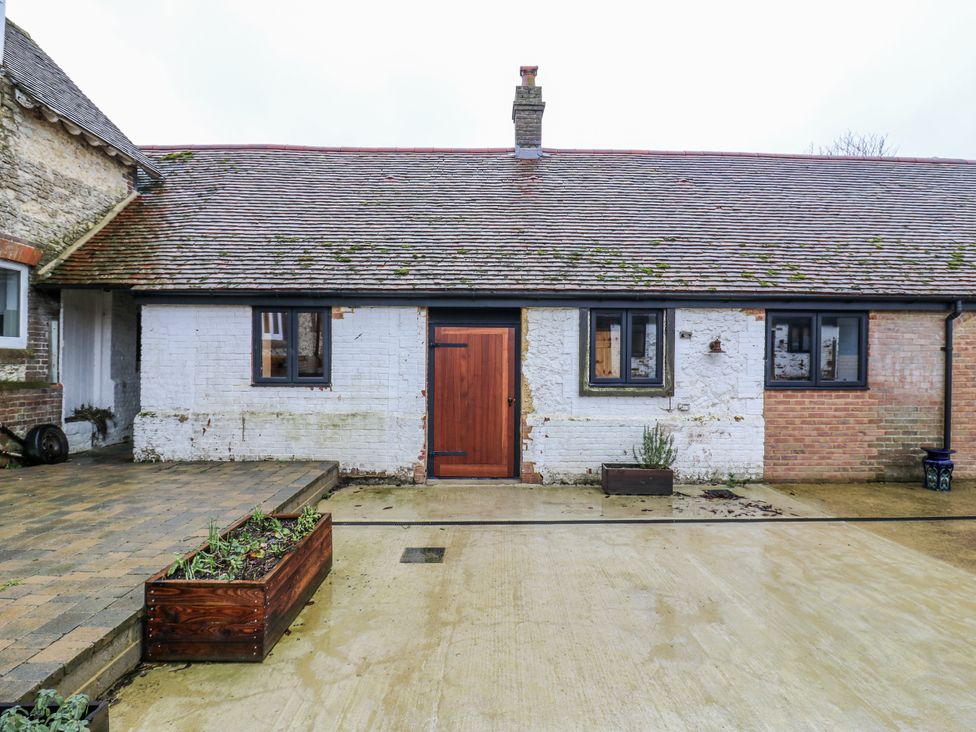 An outdoor view of a building with a brown door and windows at The Apartment Oving near Whitchurch Buckinghamshire