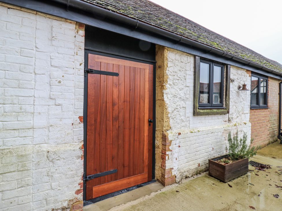 An entrance with a wooden door beside a brick wall at The Apartment in Oving near Whitchurch, Buckinghamshire