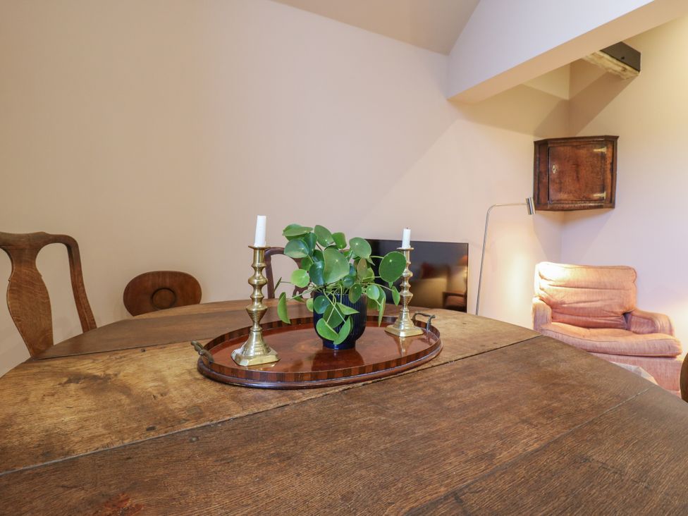 A dining table with a plant and candlesticks at The Apartment in Oving near Whitchurch, Buckinghamshire