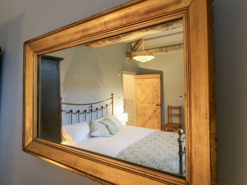 A bedroom with a bed and wardrobe visible in the mirror at The Apartment in Oving near Whitchurch, Buckinghamshire