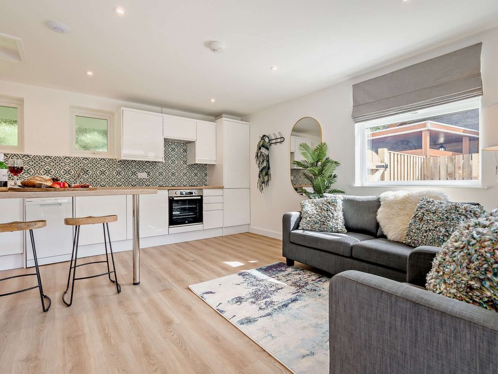 A kitchen area with white cabinets and bar stools at Klys 1.0 Spa Perranporth