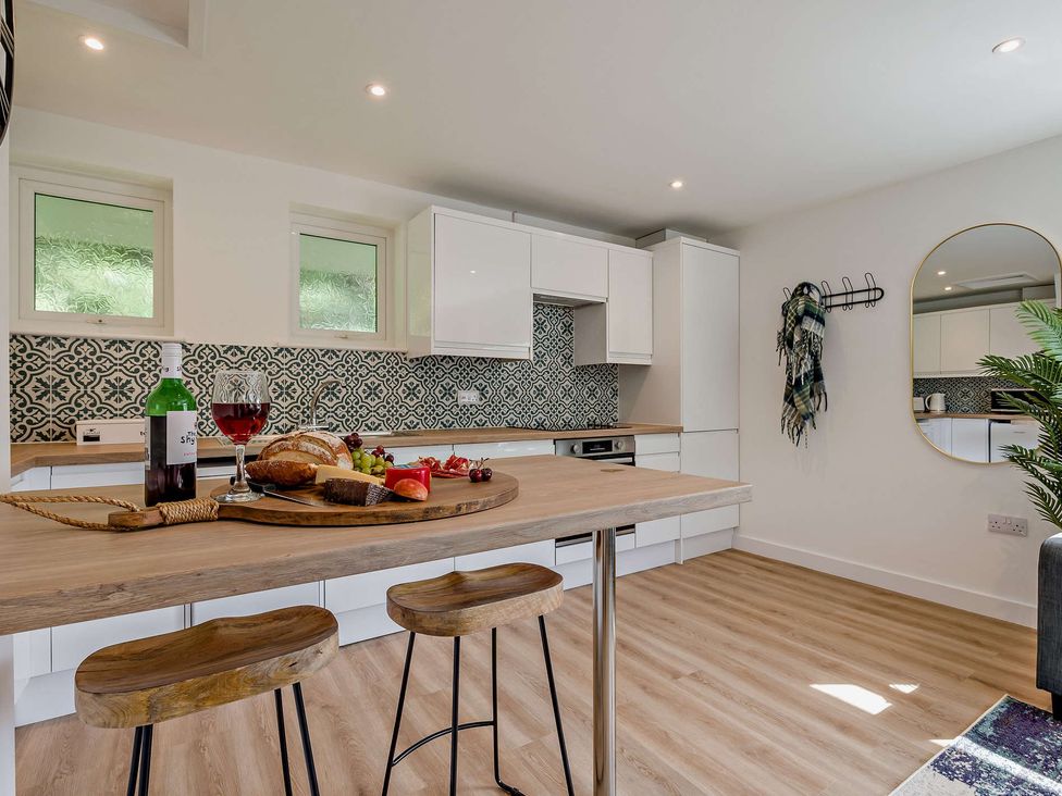 A kitchen with a table set with wine and fruits at Klys 1.0 Spa in Perranporth