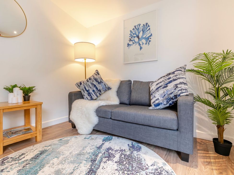 A living room with a sofa and lamp at Chapel Rock Spa Pet in Perranporth