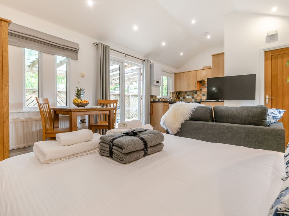 A living room with a dining table and kitchen area at Droskyn Spa Pet Perranporth