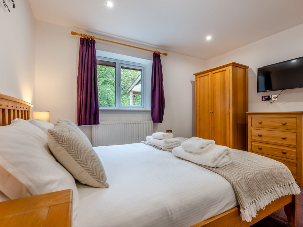 A bedroom with a bed and wardrobe at Poldark Spa Pet in Perranporth