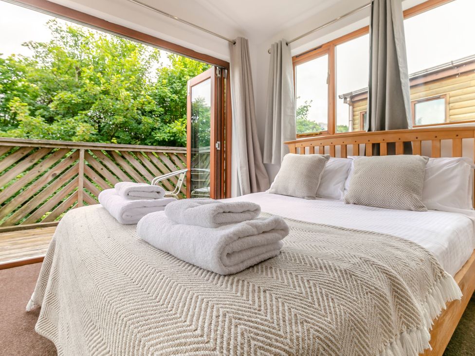 A bedroom with a bed and towels at Treehouse Spa in Perranporth